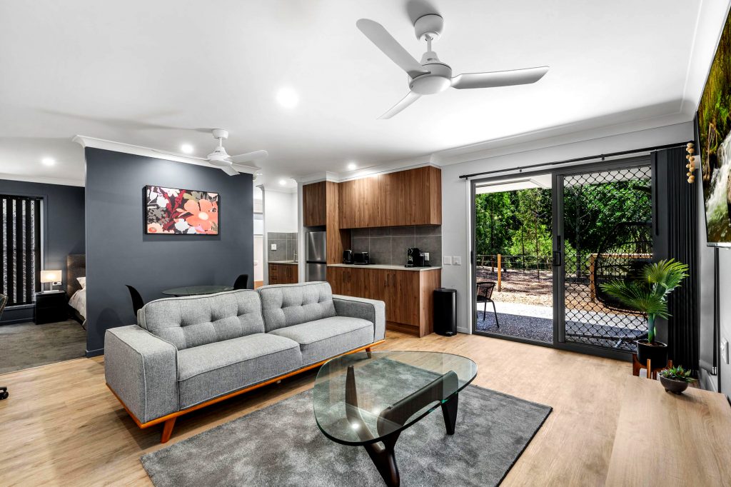 Bright modern Brisbane rooming house living room with stylish furniture and large sliding glass door.